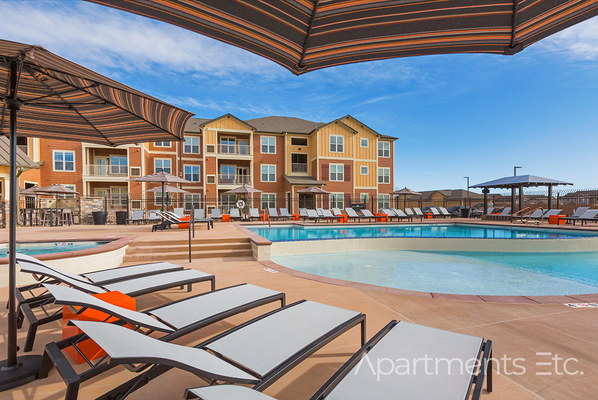 Poolside lounge chairs and swimming pool at Mesa Ridge Apartments.