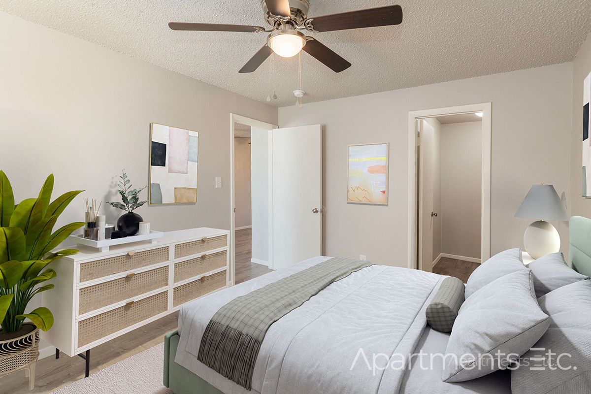 Apartment bedroom with ceiling fan, bed, and neutral interior design.